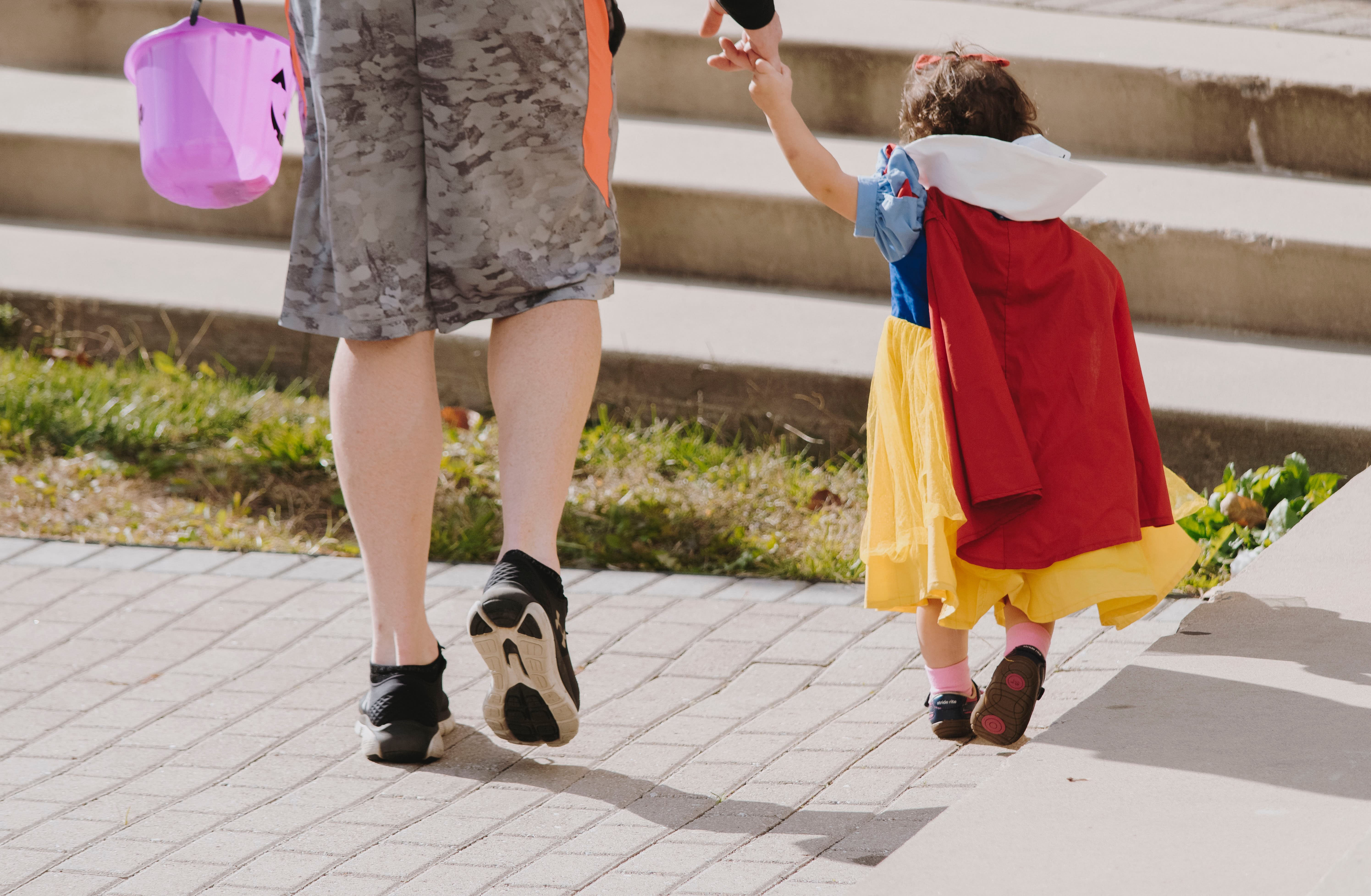 Child in Snow White costume holding an adult's hand 