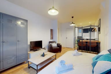 Espace de vie avec rangement, TV, lit double, coin repas et cuisine