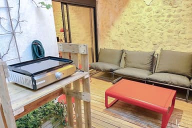 Terrasse intime et chaleureuse avec sièges confortables et table basse rouge...