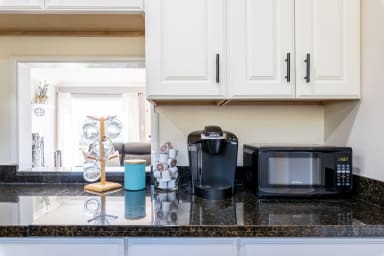 Sleek kitchen corner with microwave, coffee machine, and ample storage