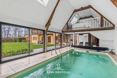Piscine intérieure lumineuse avec vues sur le jardin, parfaite pour la détente.