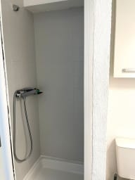 Salle d'eau avec douche, sèche-cheveux, et toilettes