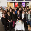 Deborah Shaw cuts a celebratory cake surrounded by theatre chaplains, theatre staff and stars from Cinderella