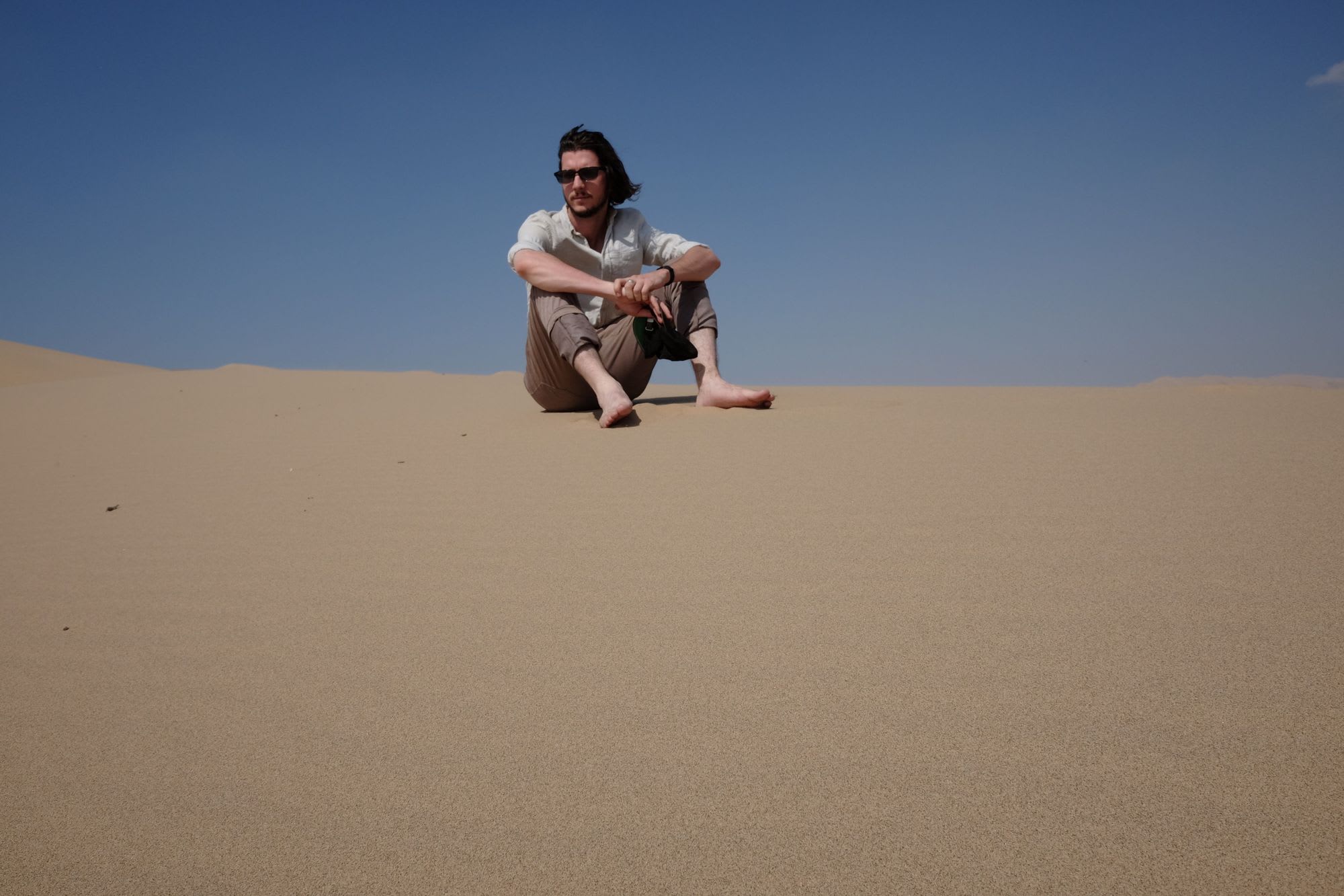Josh sitting on a sand dune in the Gobi Desert, Mongolia.
