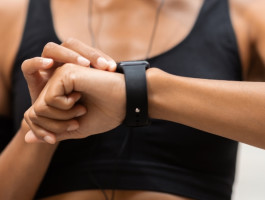 Eine Frau in Sportkleidung blickt auf ihre Smartwatch.