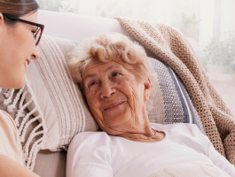 Pflegefachkraft im Gespräch mit einer älteren Patientin bei der außerklinischen Intensivpflege zu Hause.
