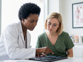 Ärztin bespricht mit einer Patientin medizinische Untersuchungsergebnisse auf einem Tablet.