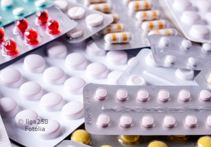 Verschiedene Blisterpackungen mit Tabletten und Kapseln in unterschiedlichen Farben (weiß, rosa, gelb, rot). Die Packungen sind überlappend angeordnet und bilden einen unordentlichen Haufen.