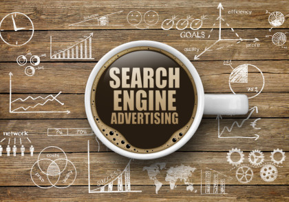 Eine Kaffeetasse auf einem Holztisch, gefüllt mit Kaffee, auf dem "Search Engine Advertising" steht. Um die Tasse herum sind Diagramme, Grafiken und Symbole mit Begriffen wie "Goals", "Quality" und "Efficiency" gezeichnet.