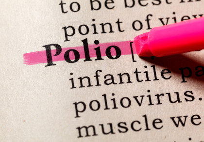 Nahaufnahme des Wortes "Polio" in einem Wörterbuch, das mit einem rosa Textmarker hervorgehoben wird.