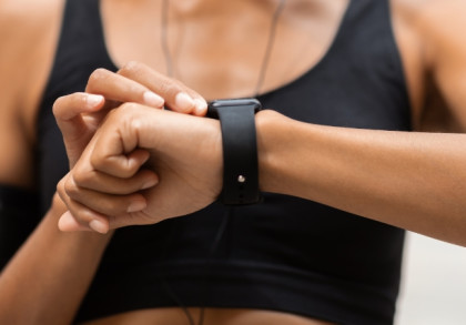 Eine Frau in Sportkleidung blickt auf ihre Smartwatch.