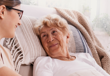Pflegefachkraft im Gespräch mit einer älteren Patientin bei der außerklinischen Intensivpflege zu Hause.