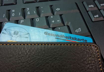 Elektronische Gesundheitskarte in einer Geldbörse vor einer Computertastatur als Symbol für die digitale Gesundheitsversorgung.