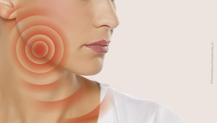 Nahaufnahme eines Gesichts auf der rechten Seite mit einem roten, kreisförmigen Schmerzsymptom oberhalb des Kiefers und des Halses. Die Person trägt ein weißes Oberteil und hat leicht glänzende Lippen.