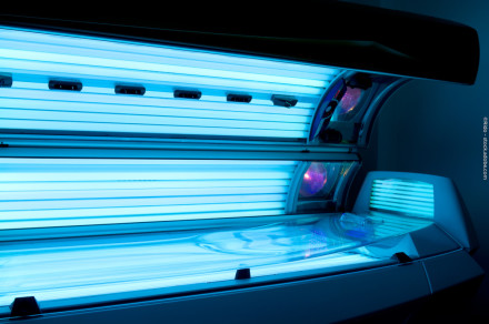 Ein Solarium mit eingeschaltetem blauem UV-Licht in einem dunklen Raum.