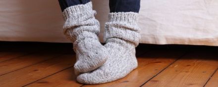 Eine Frau hat dicke Socken an und reibt sich die Füße aneinander.