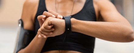Eine Frau in Sportkleidung blickt auf ihre Smartwatch.