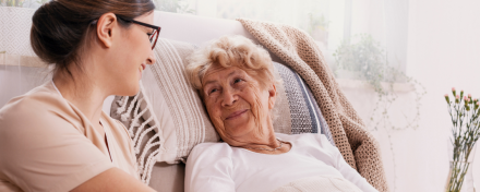 Pflegefachkraft im Gespräch mit einer älteren Patientin bei der außerklinischen Intensivpflege zu Hause.