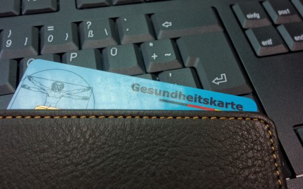 Elektronische Gesundheitskarte in einer Geldbörse vor einer Computertastatur als Symbol für die digitale Gesundheitsversorgung.