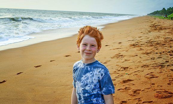 Junge auf Sandstrand lächelt in die Kamera