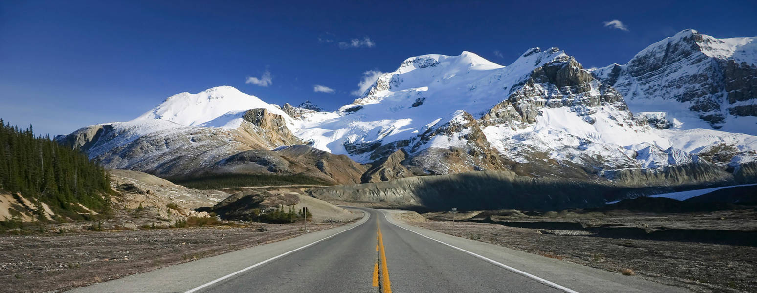 a snow covered road with a mountain in the background