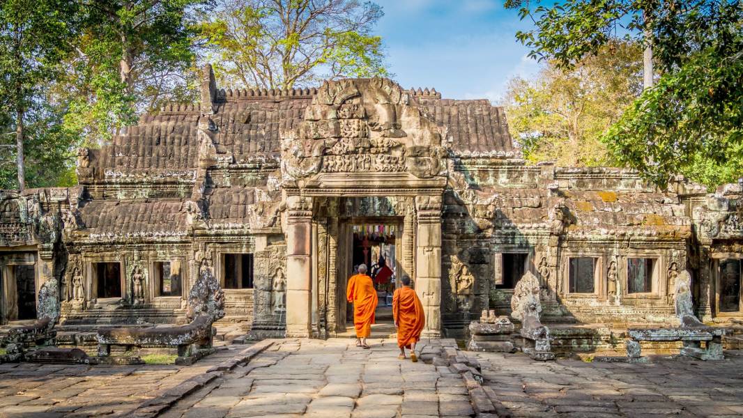 a person standing in front of a stone building with Angkor Wat in the background