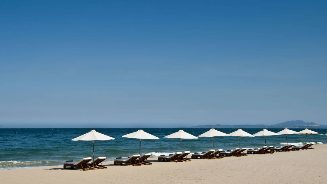 a group of lawn chairs sitting on top of a sandy beach