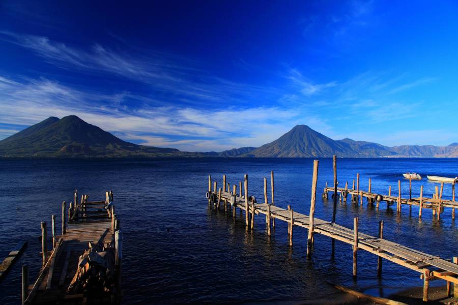 a wooden pier next to a body of water with Lake Atitlán in the background