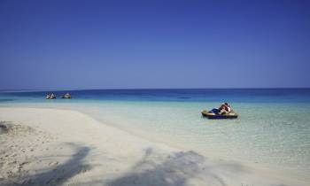 a boat sitting on top of a sandy beach next to the ocean