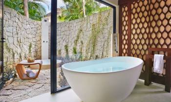 a large white tub sitting next to a stone wall