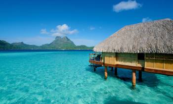 a pool next to a body of water with Bora Bora in the background