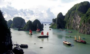 a group of people in a small boat in a body of water with Ha Long Bay in the background