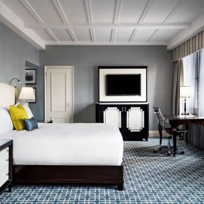 a bedroom with a bed and desk in a hotel room