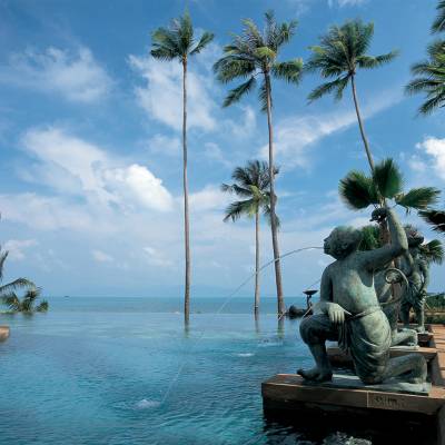 a group of palm trees next to a body of water