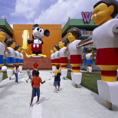a group of people sitting around a fire hydrant with Disney's Pop Century Resort in the background