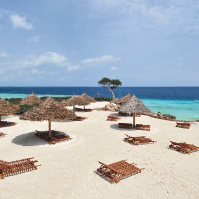 a group of lawn chairs sitting on top of a sandy beach