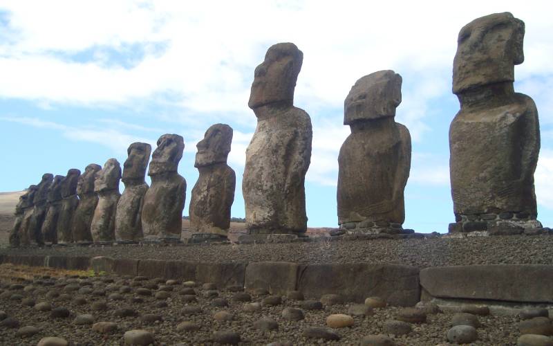 a group of people on a rock with Easter Island in the background