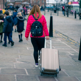 Enchanting Travels UK & Ireland Tours Blurred photo,The asian girl with pink jacket walks along street carries luggage with children in background in Albert, Liverpool, England, United Kingdom