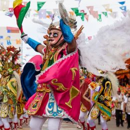 Enchanting Travels Bolivia Tours Oruro, Bolivia, carnival dancers wearing traditional masks and dresses on the street during the carnival