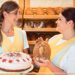 Enchanting Travels Germany Tour Sales women in bakery with cake and bread showing them to the customer
