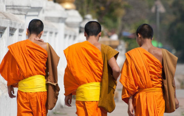 Rückansicht von drei jungen Mönchen in orangefarbener Tracht in Laos, Südostasien