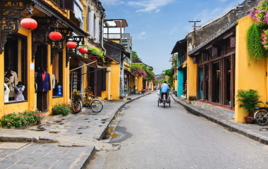 Radfahrer fährt vorbei an orangefarbenen Häusern in der Altstadt von Hoi An in Vietnam