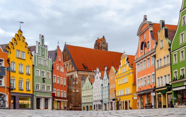 Enchanting Travels Traditional colorful gothic houses in the Old Town of Landshut, historical town in Bavaria by Munich, Germany, reflecting in a rain puddle