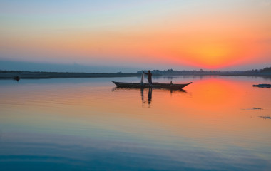 Enchanting Travels India Tours fisherman with his net and boat on the River Brahmaputra at Sunset