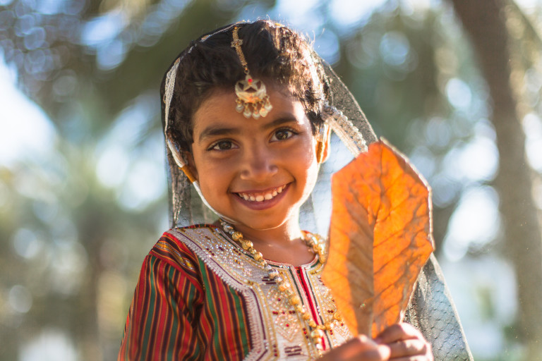 Beautiful-Omani-girl-in-traditional-dress-is-playing-in-the-park-in-Oman