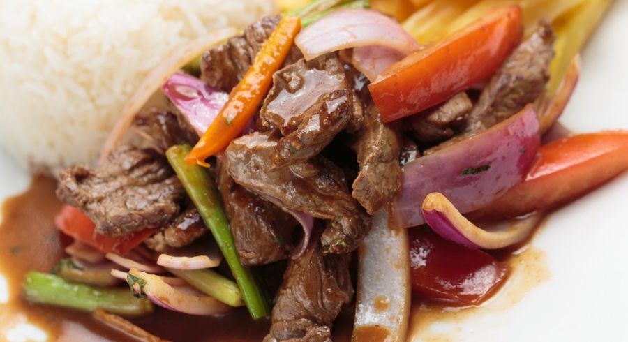 Peruvian food lomo saltado A salted beef with tomatoes, onion, fried potatoes and rice