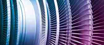 Close-up image of industrial turbine blades, showing a detailed view of the intricate metal components arranged in a circular pattern. The blades display various shades of blue and pink, highlighting the precision and engineering involved in their design.
