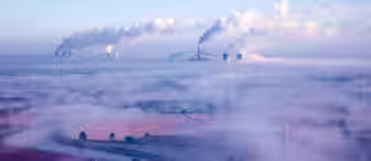 An aerial view of a foggy landscape with tall power lines and several industrial plants emitting thick plumes of smoke into the sky. The ground is partially obscured by mist, and the scene appears to be at dawn or dusk with a pale blue and pinkish hue.