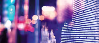 A close-up of an LED screen displays a financial graph with a cityscape in the background. The screen shows a series of dots forming line patterns, representing data. The scene is illuminated with blue and pink lights, giving it a futuristic feel.