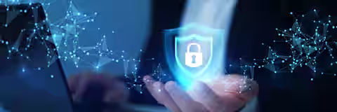 A person in a suit holds a digital shield with a padlock symbol above their hand, representing cybersecurity, in front of a laptop with abstract blue network connections.